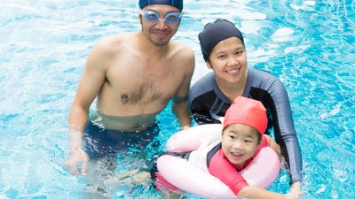 Little baby in an early swimming class with family