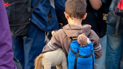 Refugee boy with toys and backpack