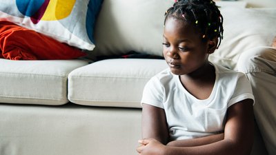 Sad girl sitting in front of a couch