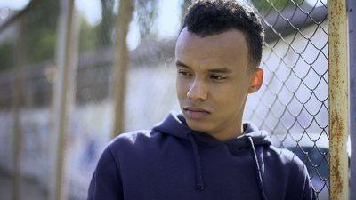 Sad teen boy at a fence