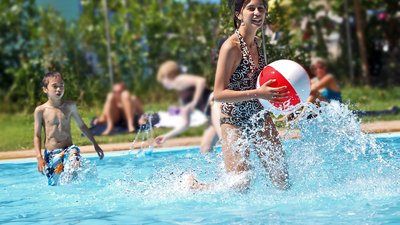 Teenage girl running with a ball in the swimming pool