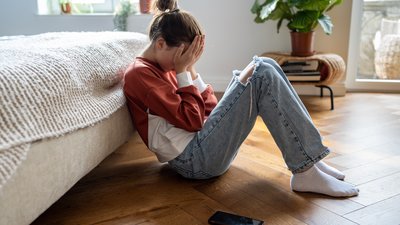 Upset girl with phone on the floor